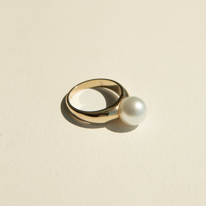Gold ring with a pearl on a beige background