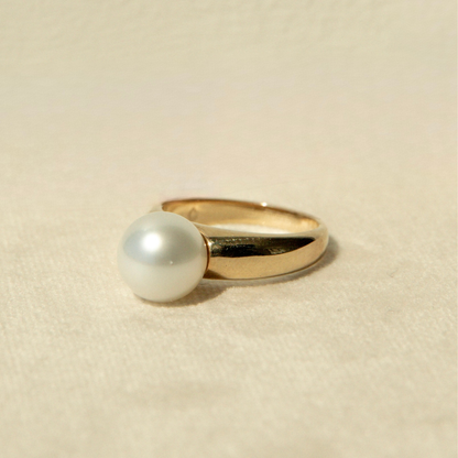 Gold ring with a pearl on a beige background
