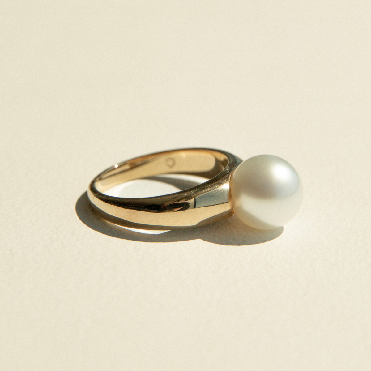 Gold ring with a pearl on a beige background