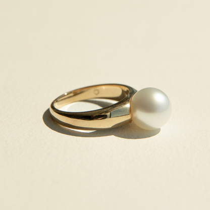 Gold ring with a pearl on a beige background