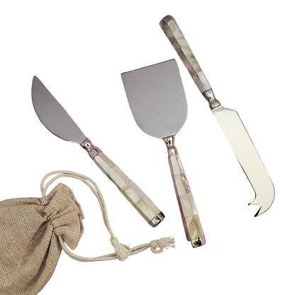 Set of three metal cheese tools with decorative handles on a checkered cloth background