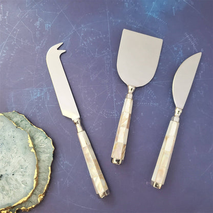 Set of three cheese knives with decorative handles on a blue surface