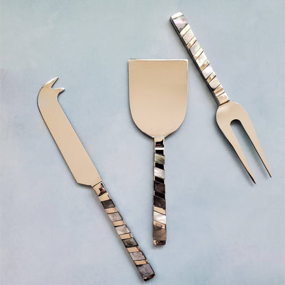 Set of three cheese tools with decorative handles on a light gray background