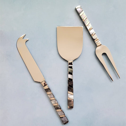 Set of three cheese tools with decorative handles on a light gray background
