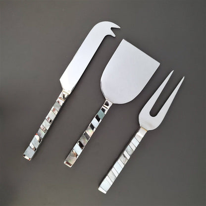 Set of three silver cheese knives on a dark gray background