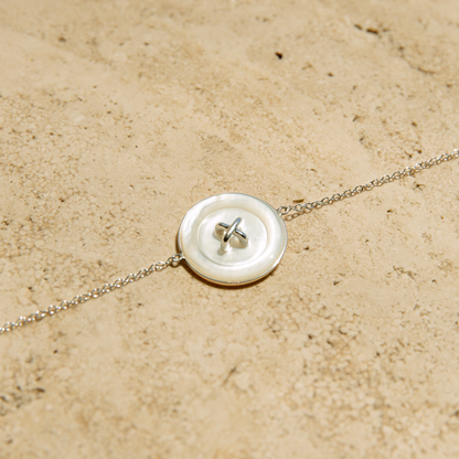 Chain bracelet with a button charm on a beige surface