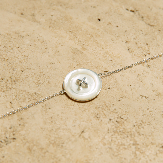 Chain bracelet with a button charm on a beige surface