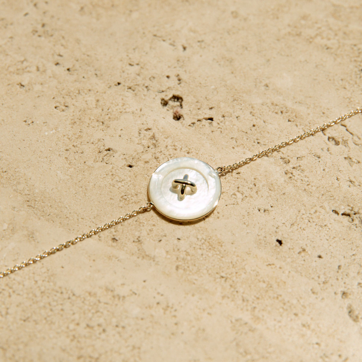 Chain bracelet with a Mother of Pearl button charm set in 9ct yellow gold. 