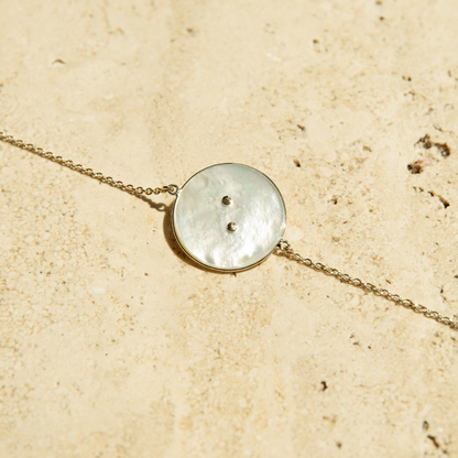 The back of the Mother of Pearl button charm on a chain bracelet.