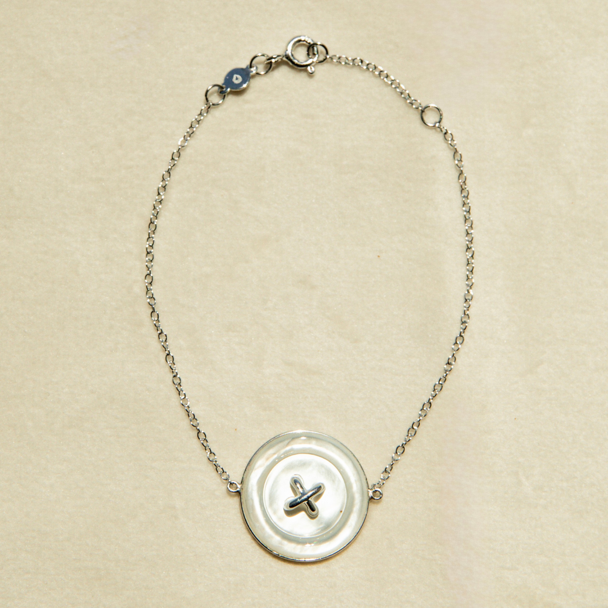 Bracelet with a Mother of Pearl button charm on a beige background