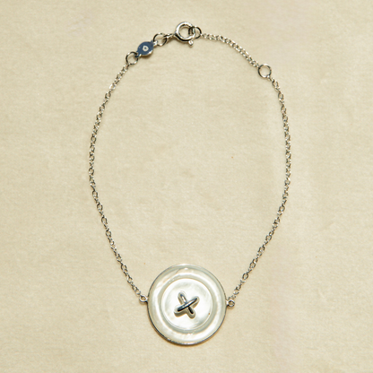 Bracelet with a Mother of Pearl button charm on a beige background