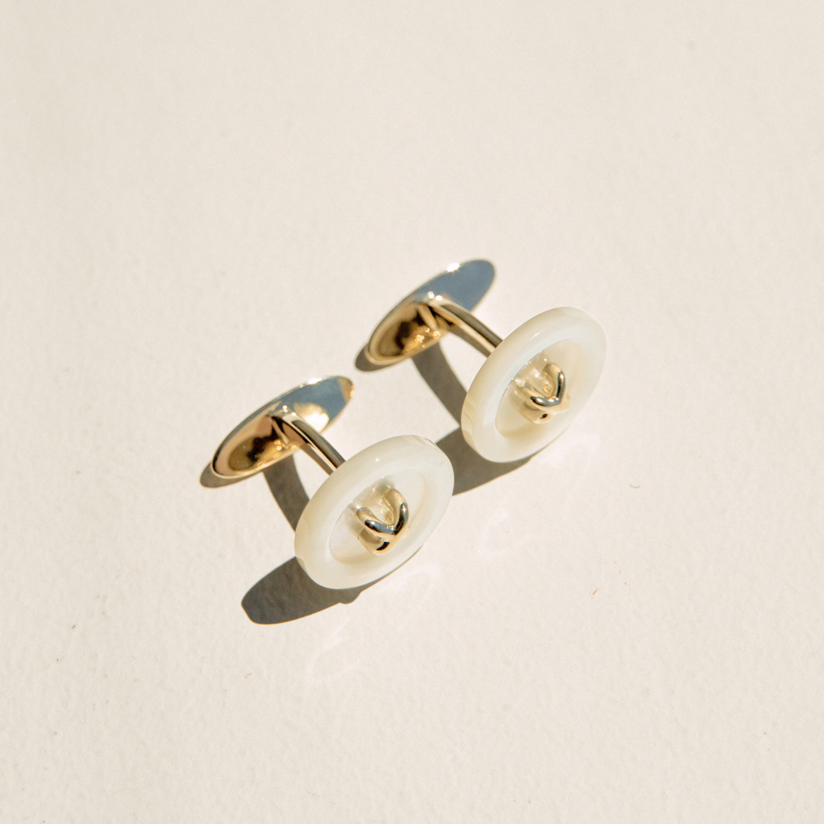 Pair of gold and Mother of pearl cufflinks on a beige background