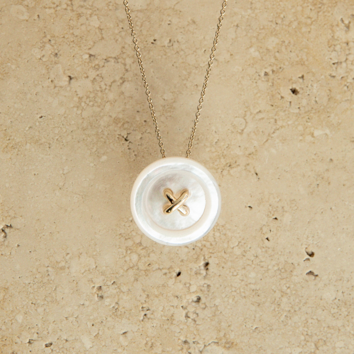 Necklace with a Mother of Pearl button on a beige textured background
