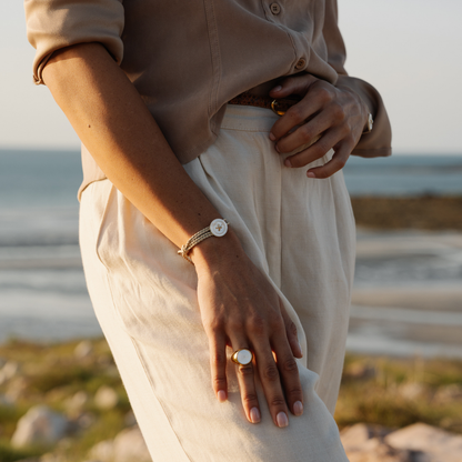 Person wearing a Mother of pearl bracelet and Mother of Pearl ring with a blurred natural background
