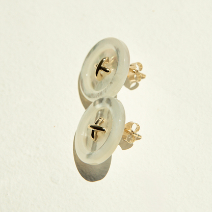 Pair of Mother of Pearl button earrings on a light beige background