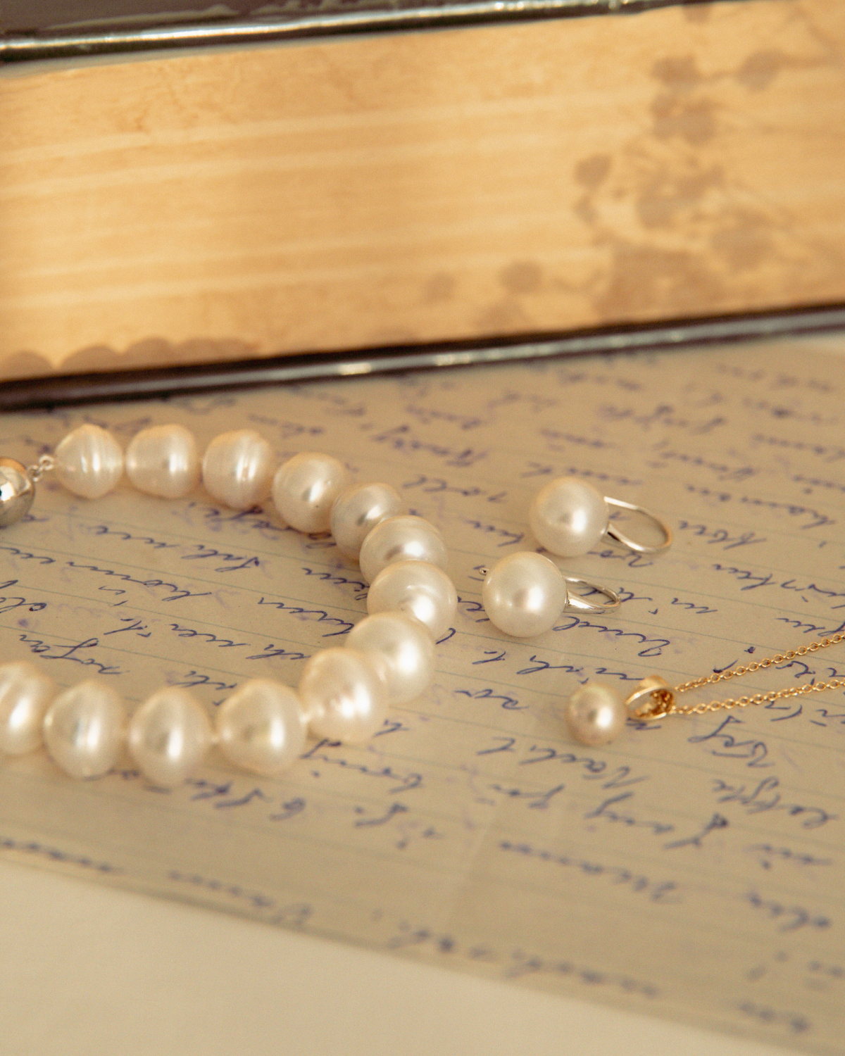 Pearl strand bracelet, pearl hooks and a pearl necklace on an open book with handwritten text