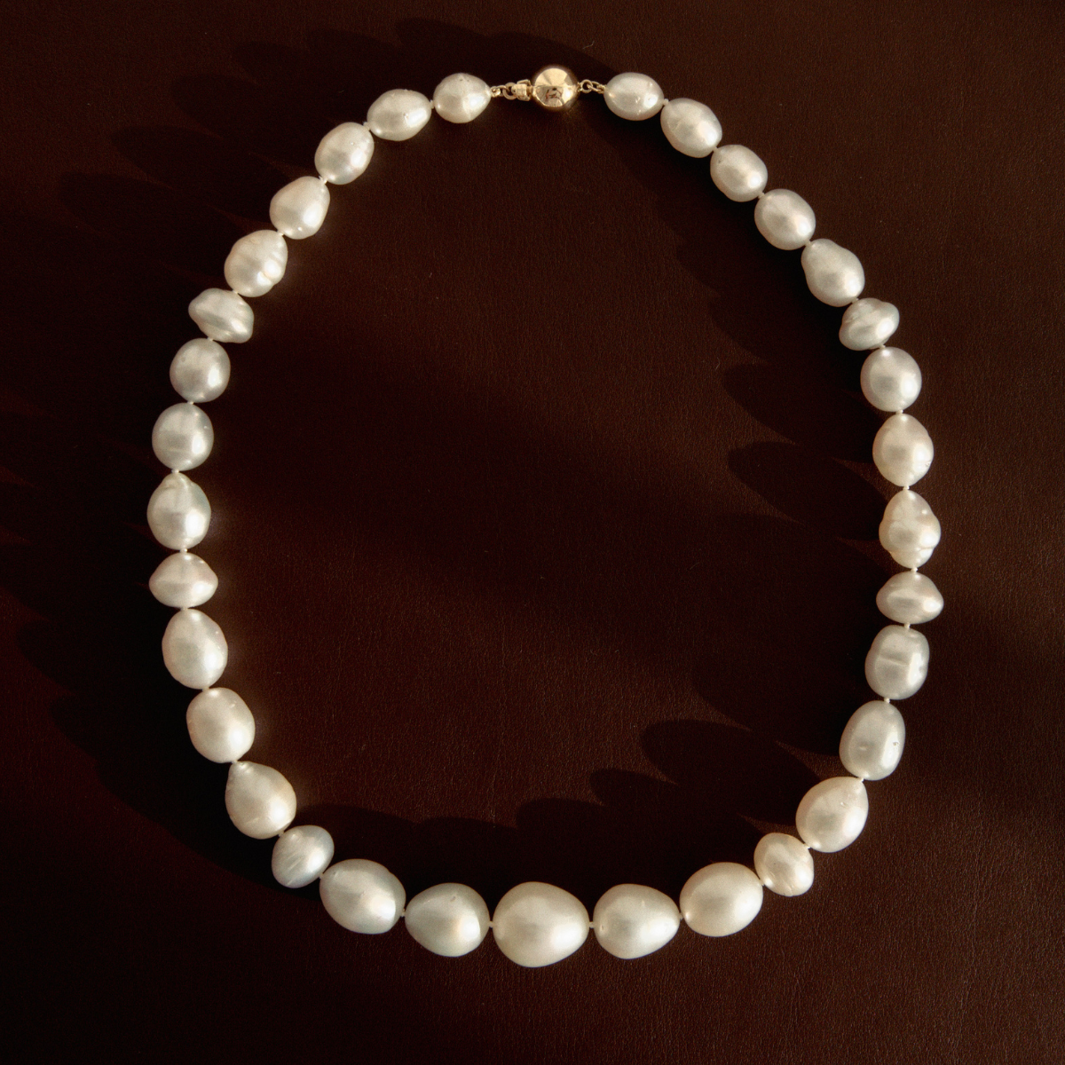 Baroque pearl strand necklace on a dark reflective surface