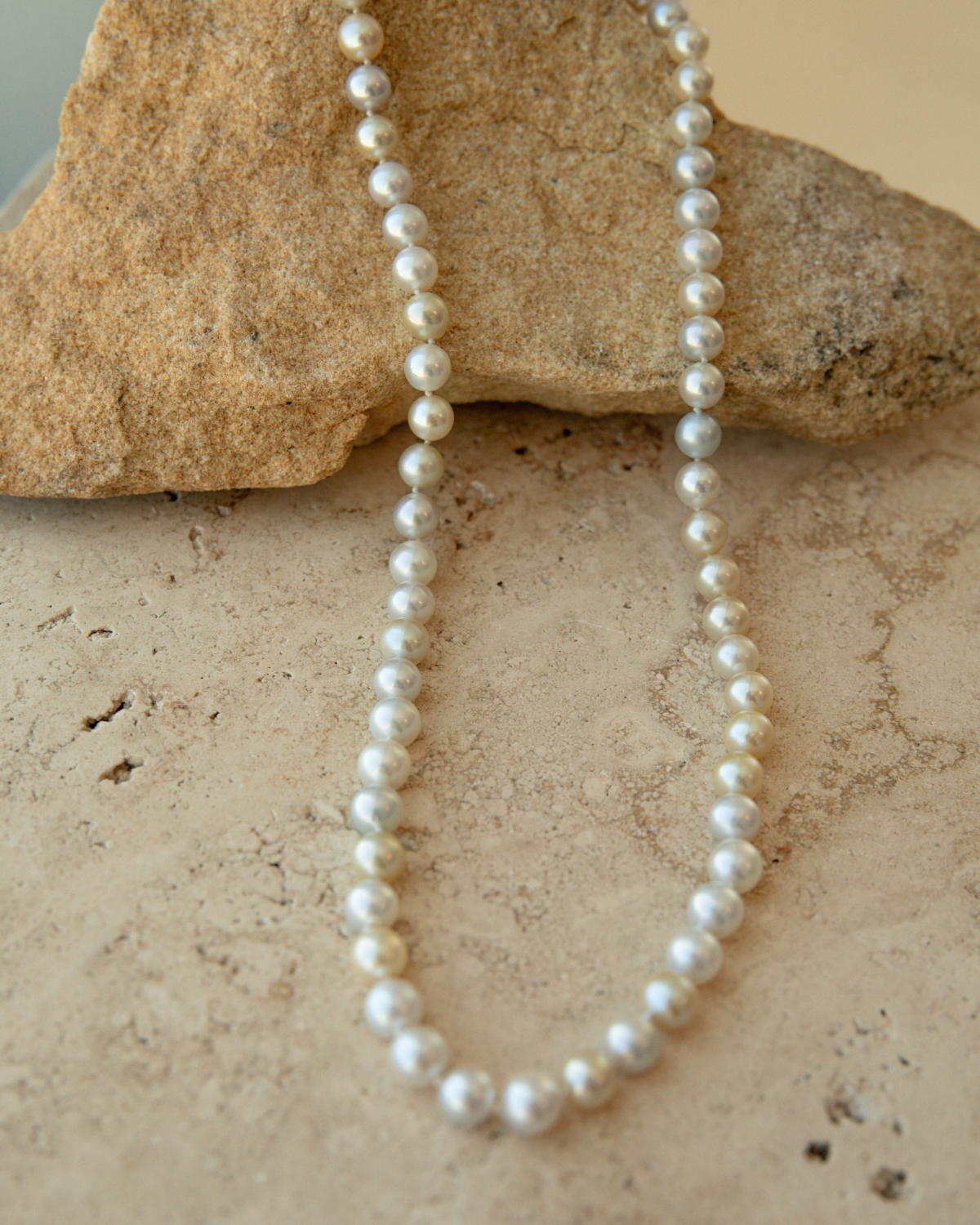 Akoya Pearl strand necklace on a textured stone surface