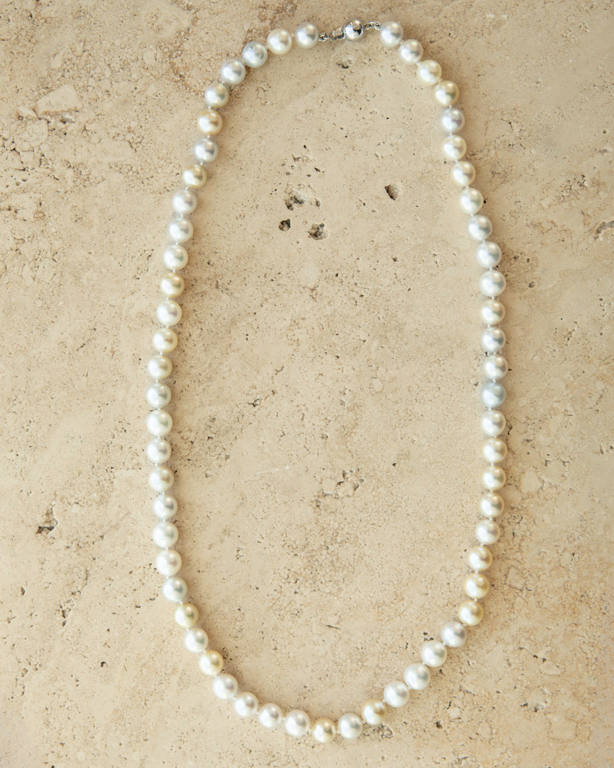 Pearl necklace on a beige stone surface