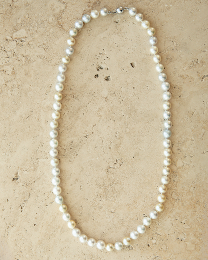 Pearl necklace on a beige stone surface