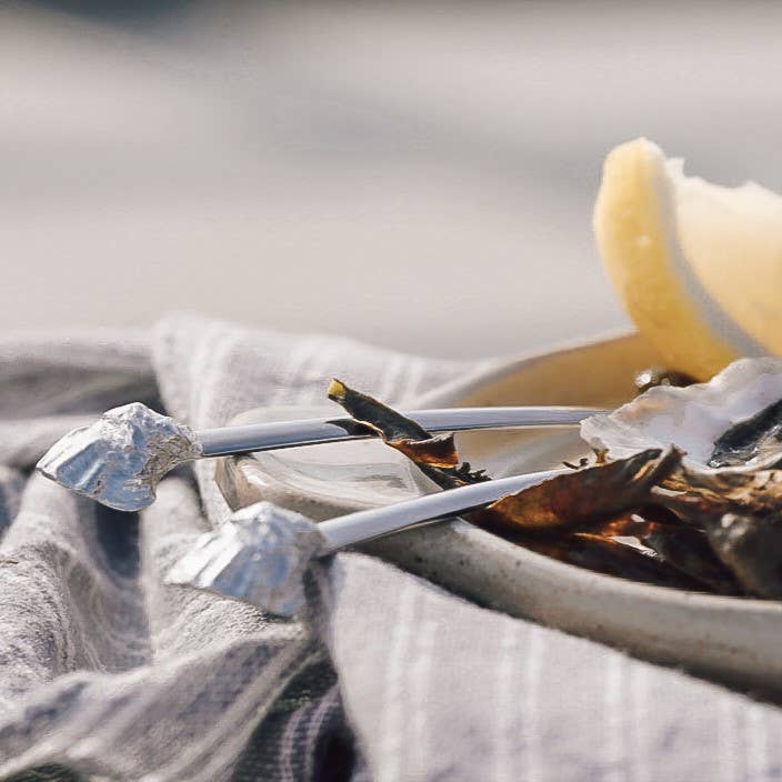 Oysters on a bed of ice with lemon wedges on a gray cloth.