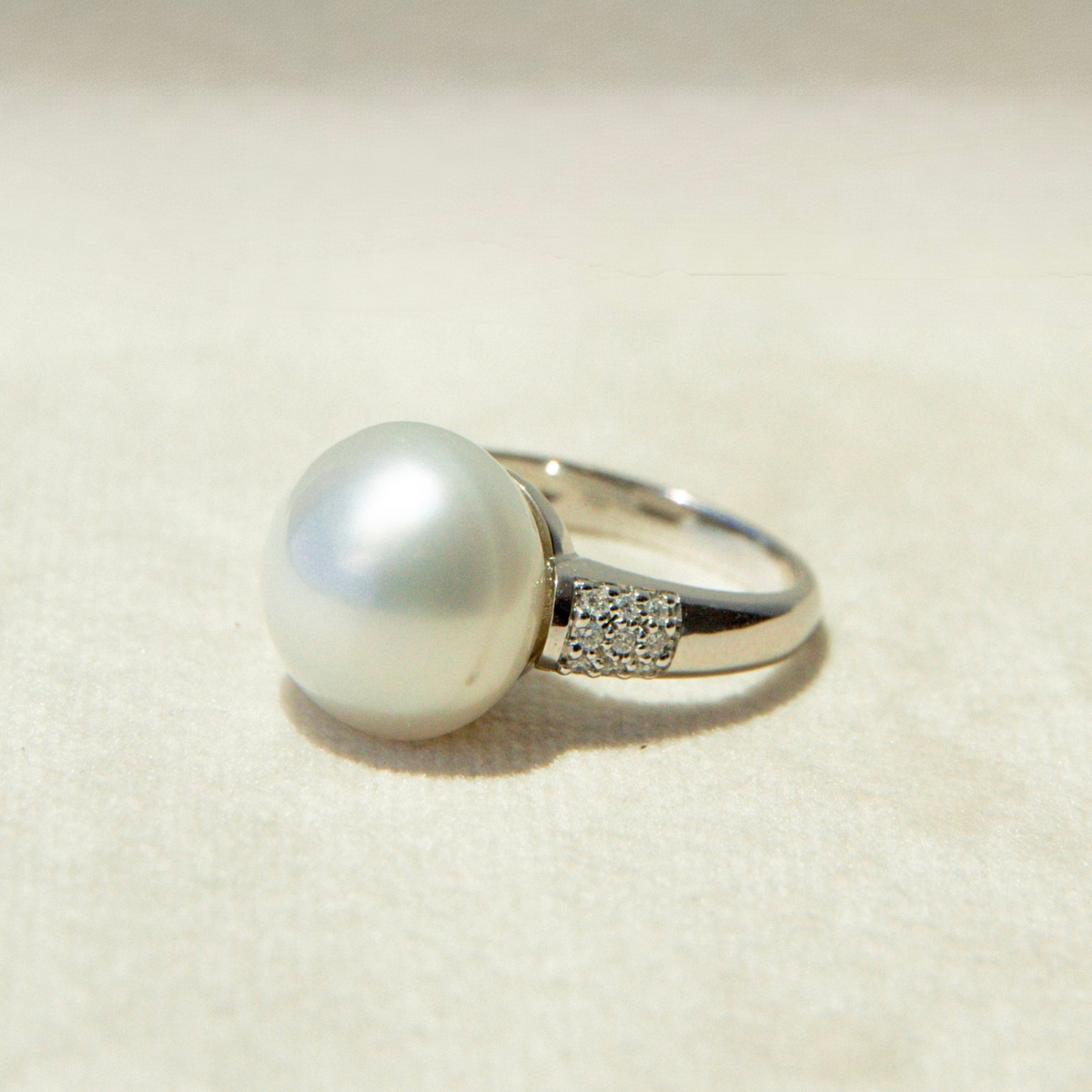 Pearl ring with a silver band on a beige background