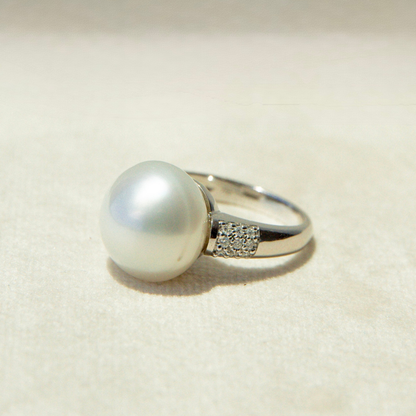 Pearl ring with a silver band on a beige background