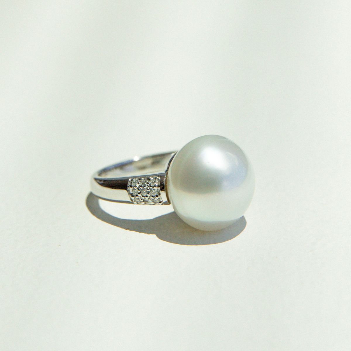 Pearl ring with silver band on a light gray background