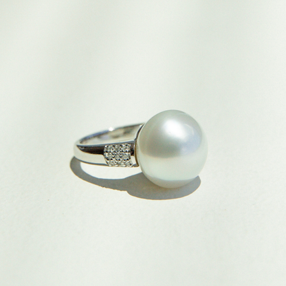 Pearl ring with silver band on a light gray background