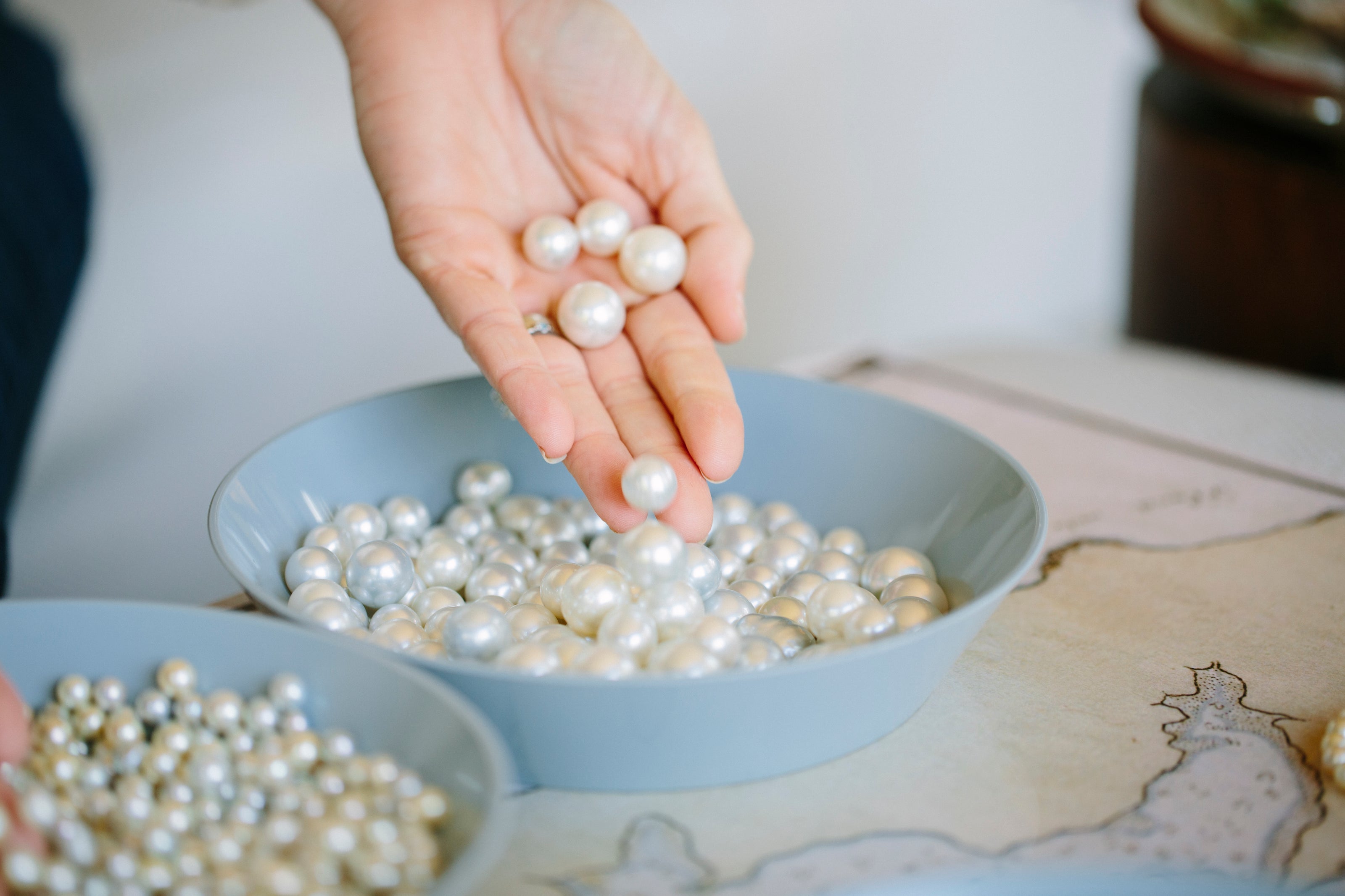 A photo of a guests hands during a Pearl Masterclass, touching an array of beautiful round Australian South Sea pearls, all in a different colours and shapes.