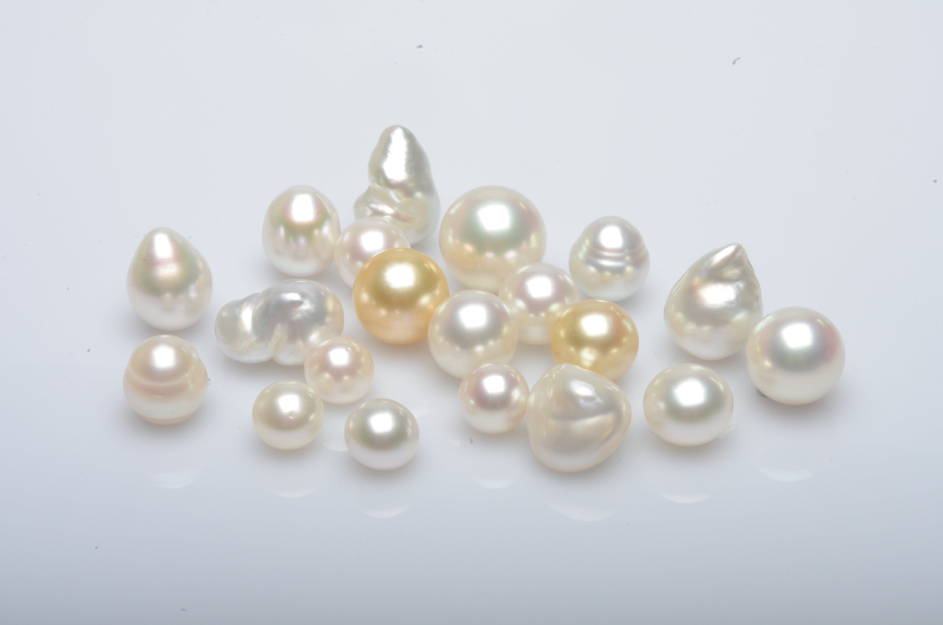 An array of different pearl shapes, in different colours, all shining with their natural colour and lustre.