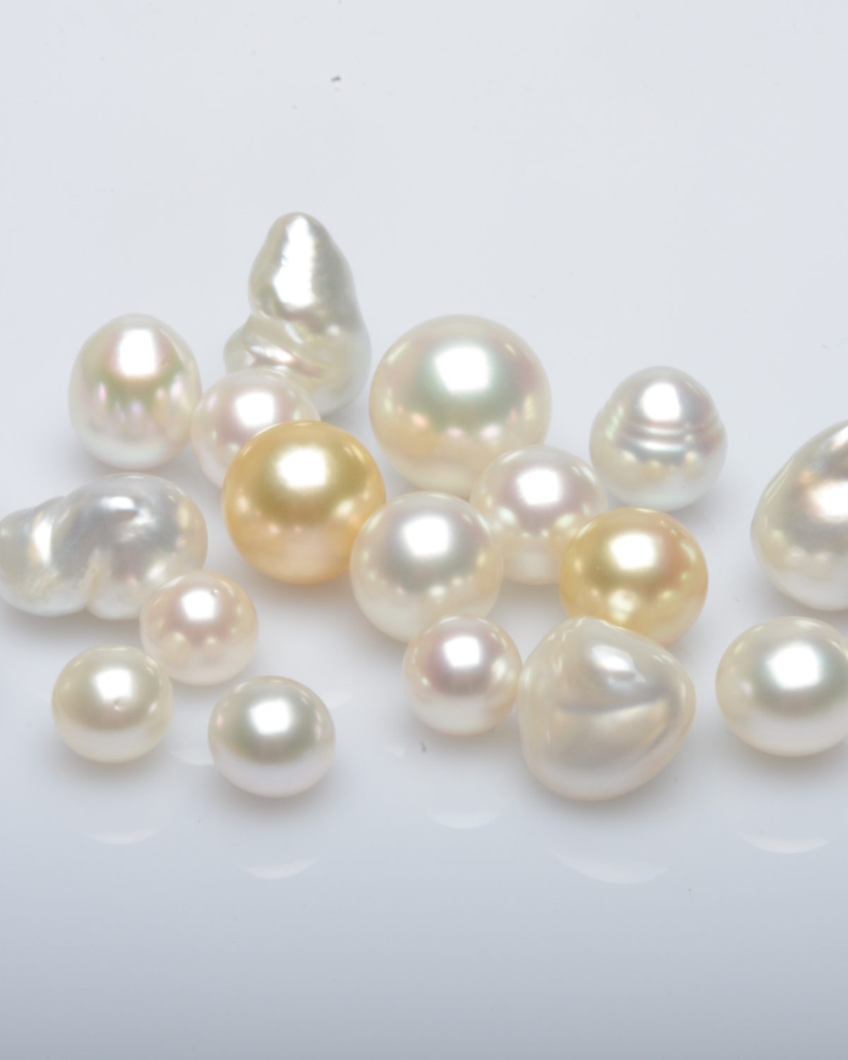 Assorted loose pearls in various shapes and colors on a light background