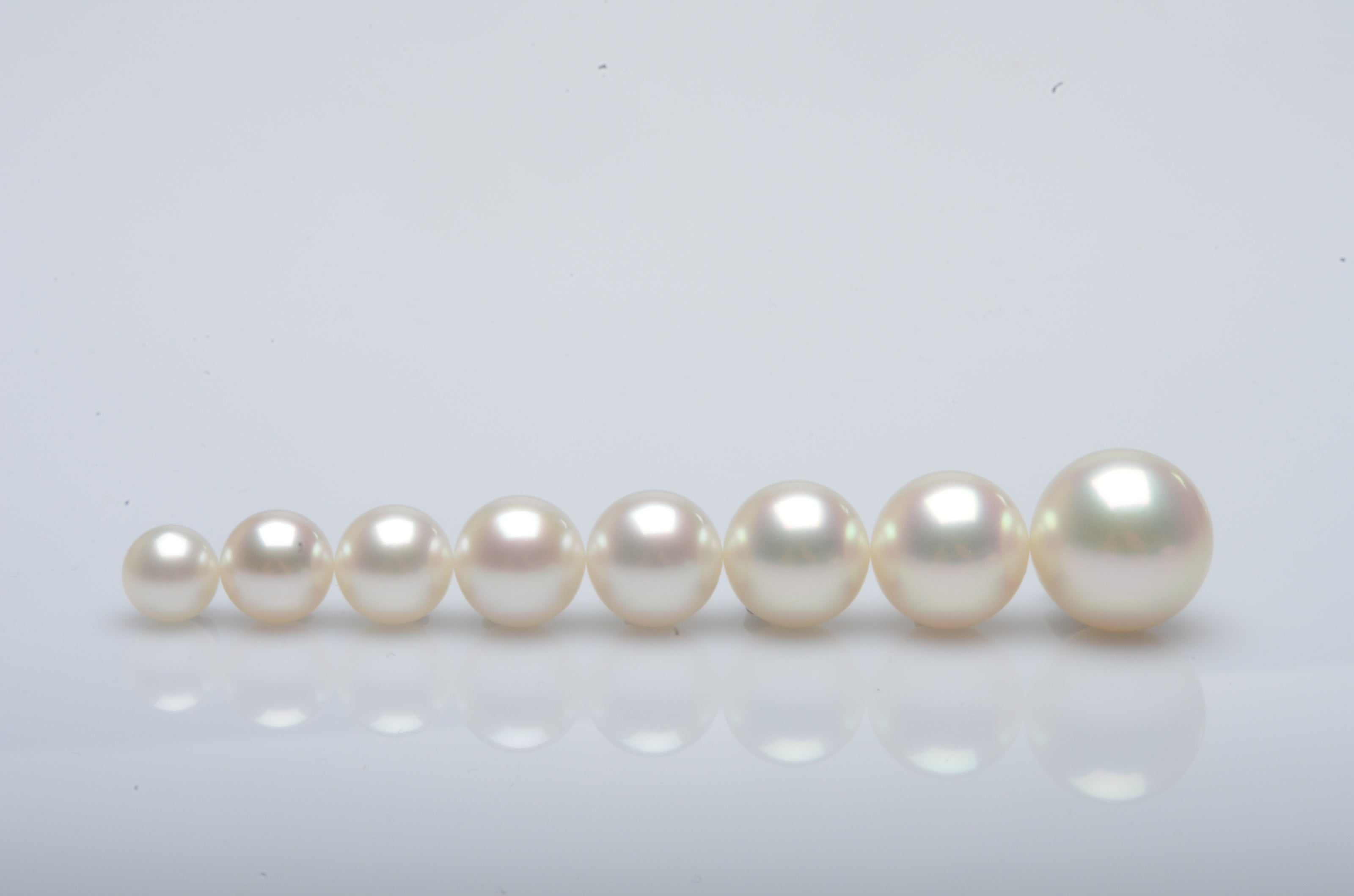 A row of pearls in order from smallest to largest, all showcasing their natural colour and lustre.