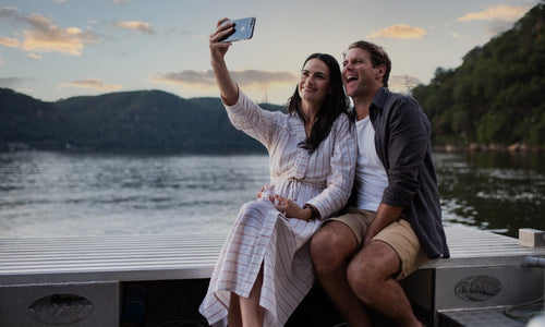 A couple enjoy their private experience at the Shellar Door, smiling and taking a selfie with a beautiful sunset in the background.