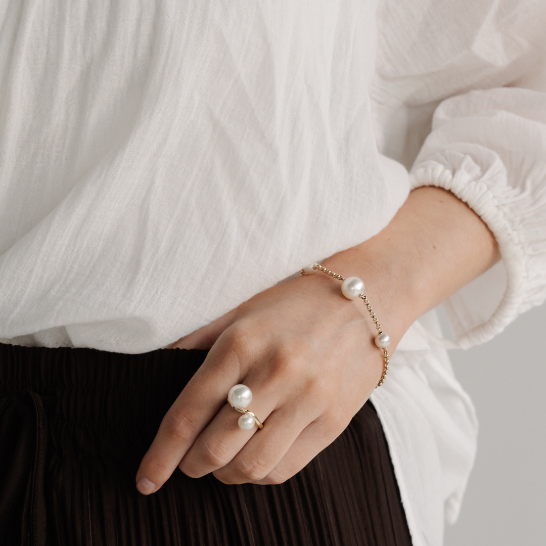 A woman wears a Provenance Bracelet featuring a Cygnet Bay (WA) grown Australian South Sea pearl and two Broken Bay (NSW) grown Australian Akoya pearls set on a gold chain.