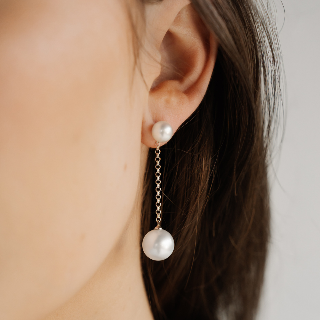 A woman wears her Provenance Pearl Earrings features a Cygnet Bay (WA) grown Australian South Sea pearl and two Broken Bay (NSW) grown Australian Akoya pearls set on a gold chain.