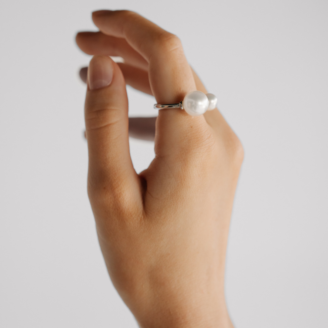 A person wears her Provenance Open Pearl Ring features a Cygnet Bay (WA) grown Australian South Sea pearl alongside a Broken Bay (NSW) grown Australian Akoya pearl set on a gold band.