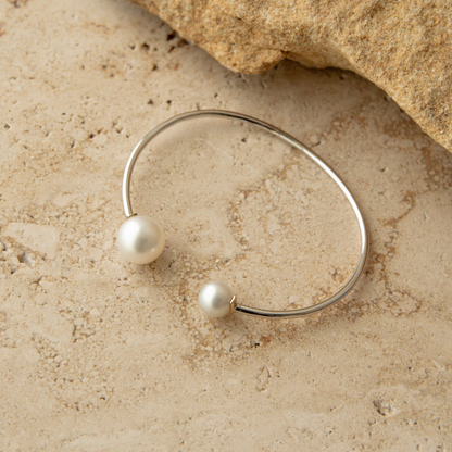 Silver bracelet with South Sea and Akoya pearls on a beige stone surface