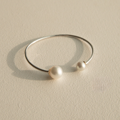 Silver bracelet with South Sea and Akoya pearls on a beige stone surface