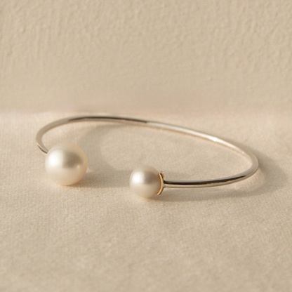 Silver bracelet with South Sea and Akoya pearls on a beige stone surface