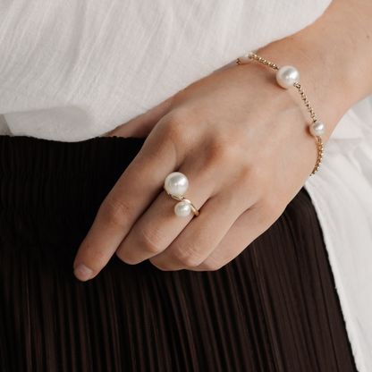 A woman wears her Provenance Pearl Twist Ring features a Cygnet Bay (WA) grown Australian South Sea pearl alongside a Broken Bay (NSW) grown Australian Akoya pearl set on a gold band.