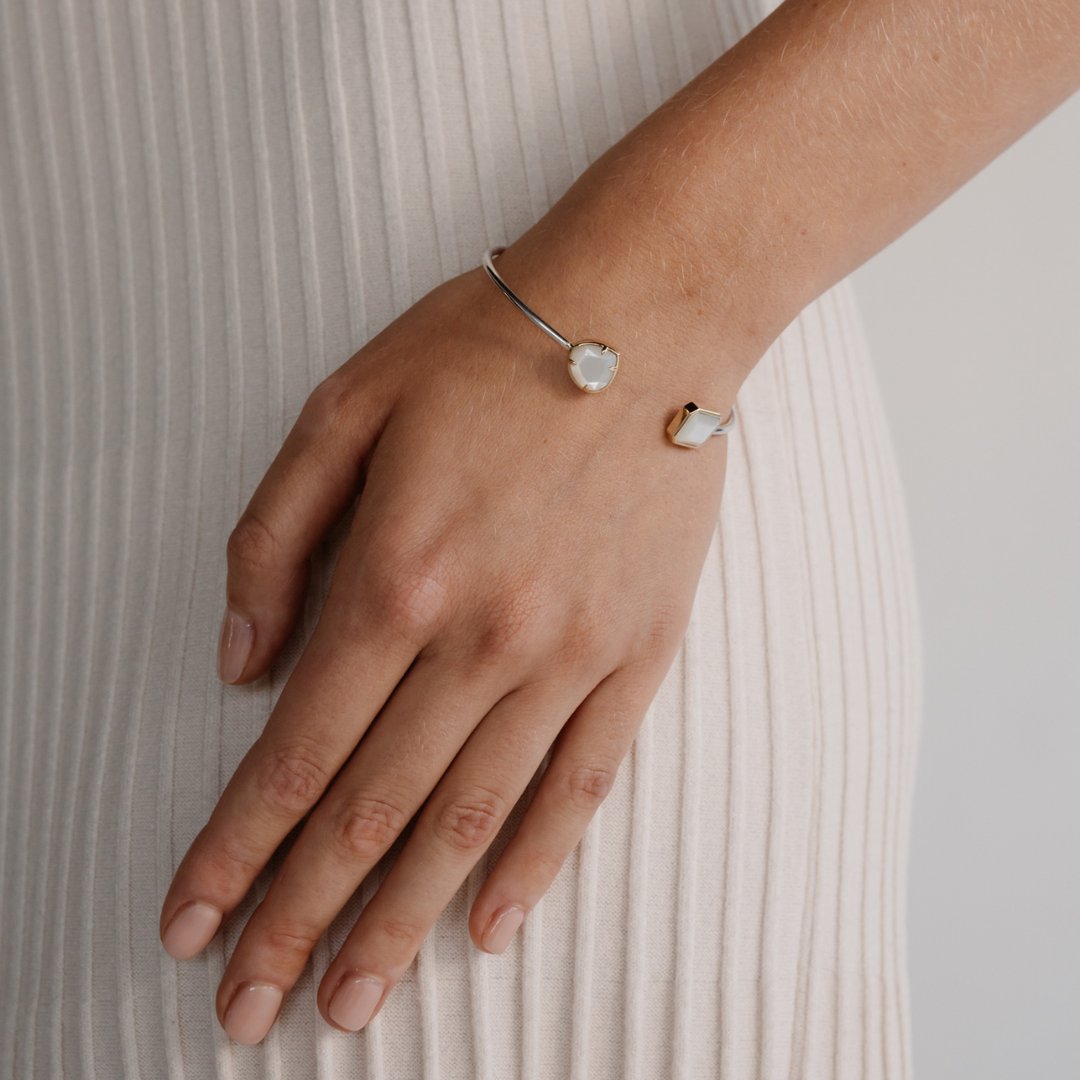 A woman wears her Radiance Emerald & Pear Cut Bangle features faceted Mother of Pearl grown at our Cygnet Bay Pearl Farm (WA).