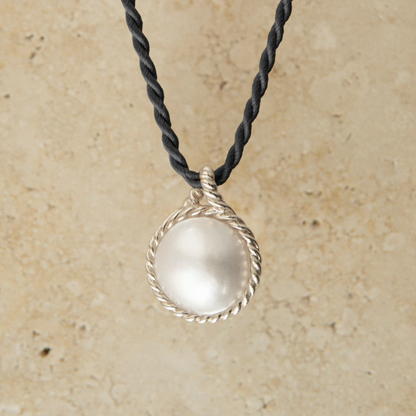Necklace with a silver Mabe pearl pendant on a beige background
