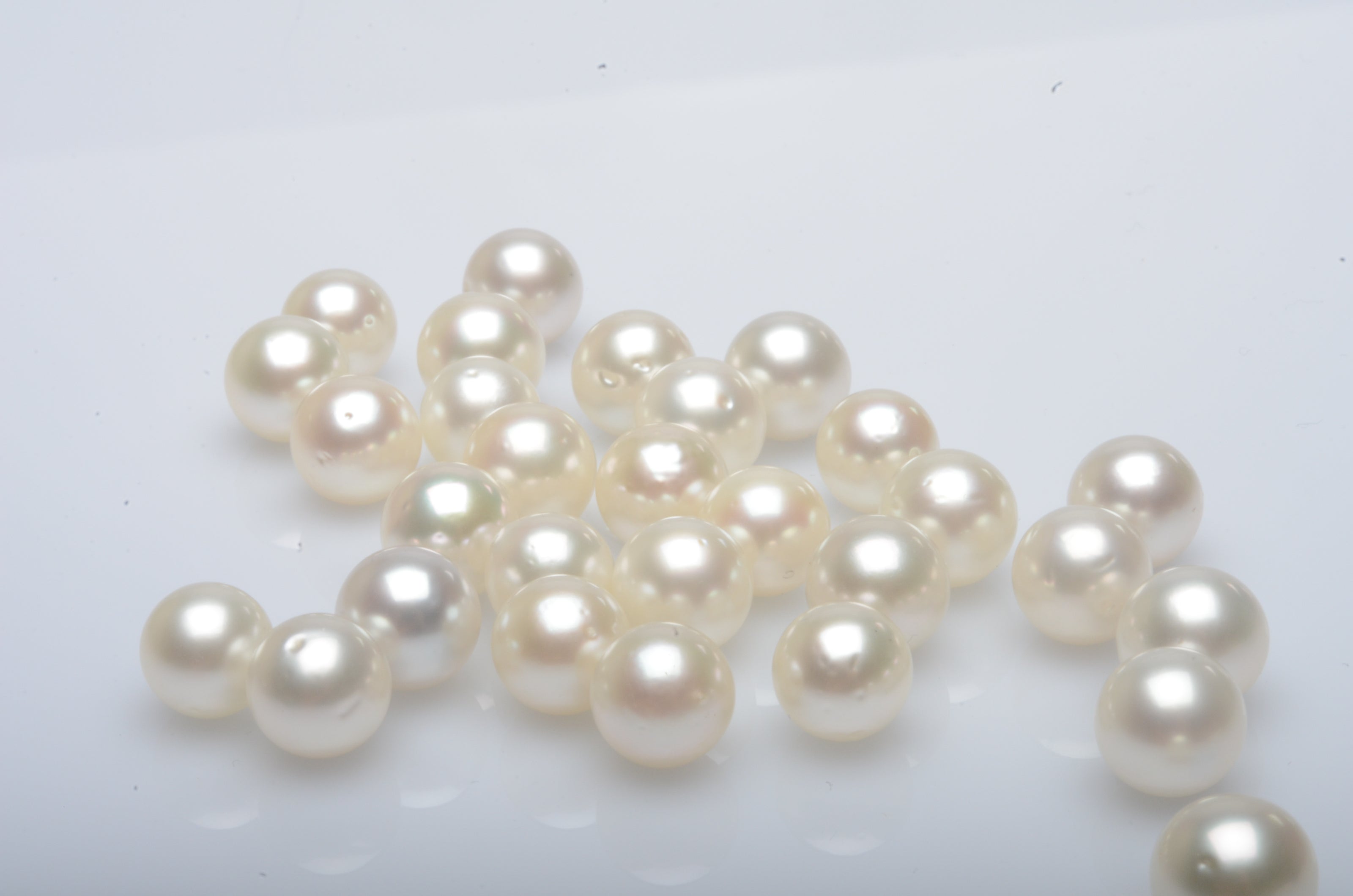 A group of round pearls, of varying surface qualities, shining with their natural colour and lustre.