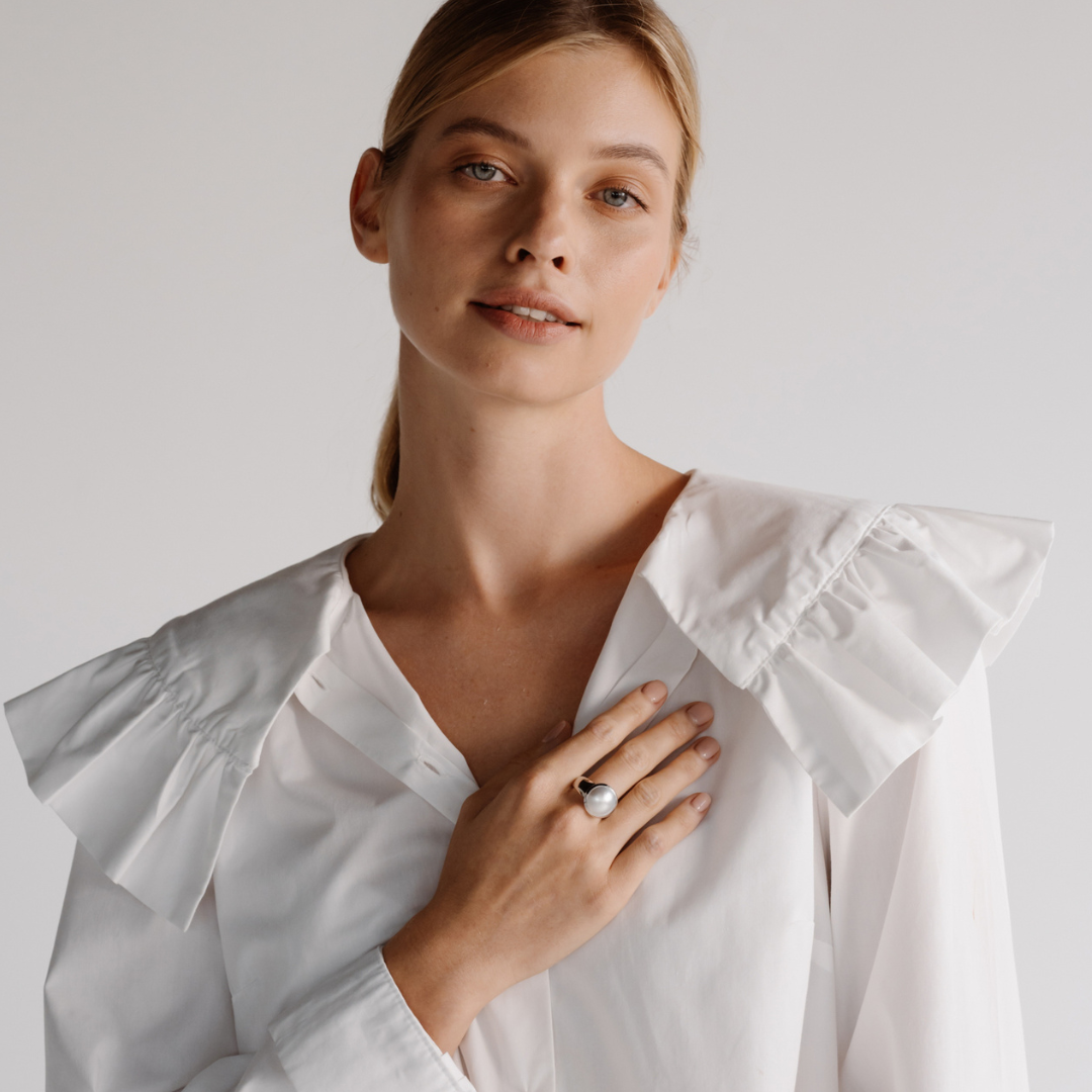 A woman wears her Save the Children Pearl Ring featuring a Cygnet Bay (WA) grown Australian South Sea Mabe pearl set in gold or sterling silver.