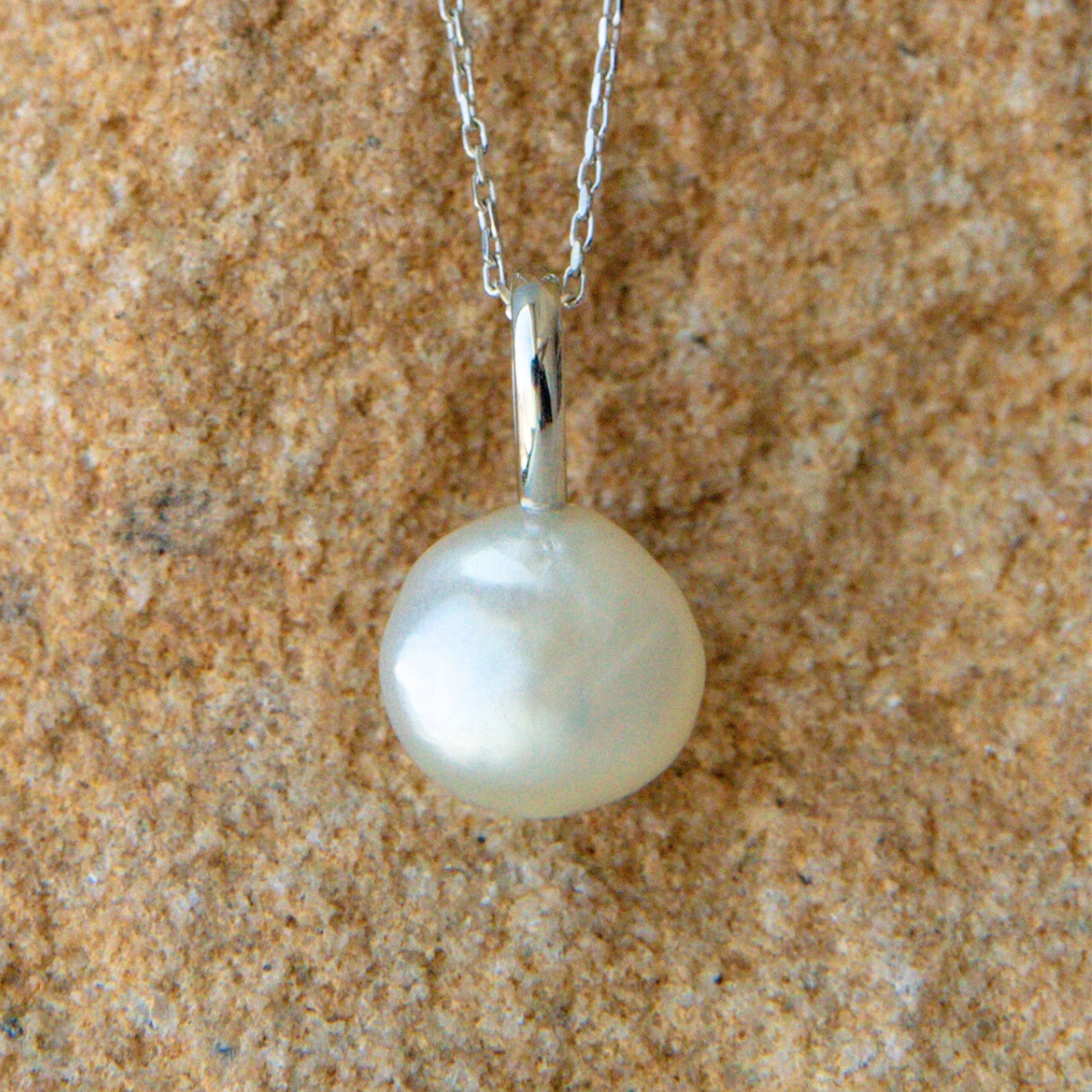 Pearl necklace on a textured beige surface