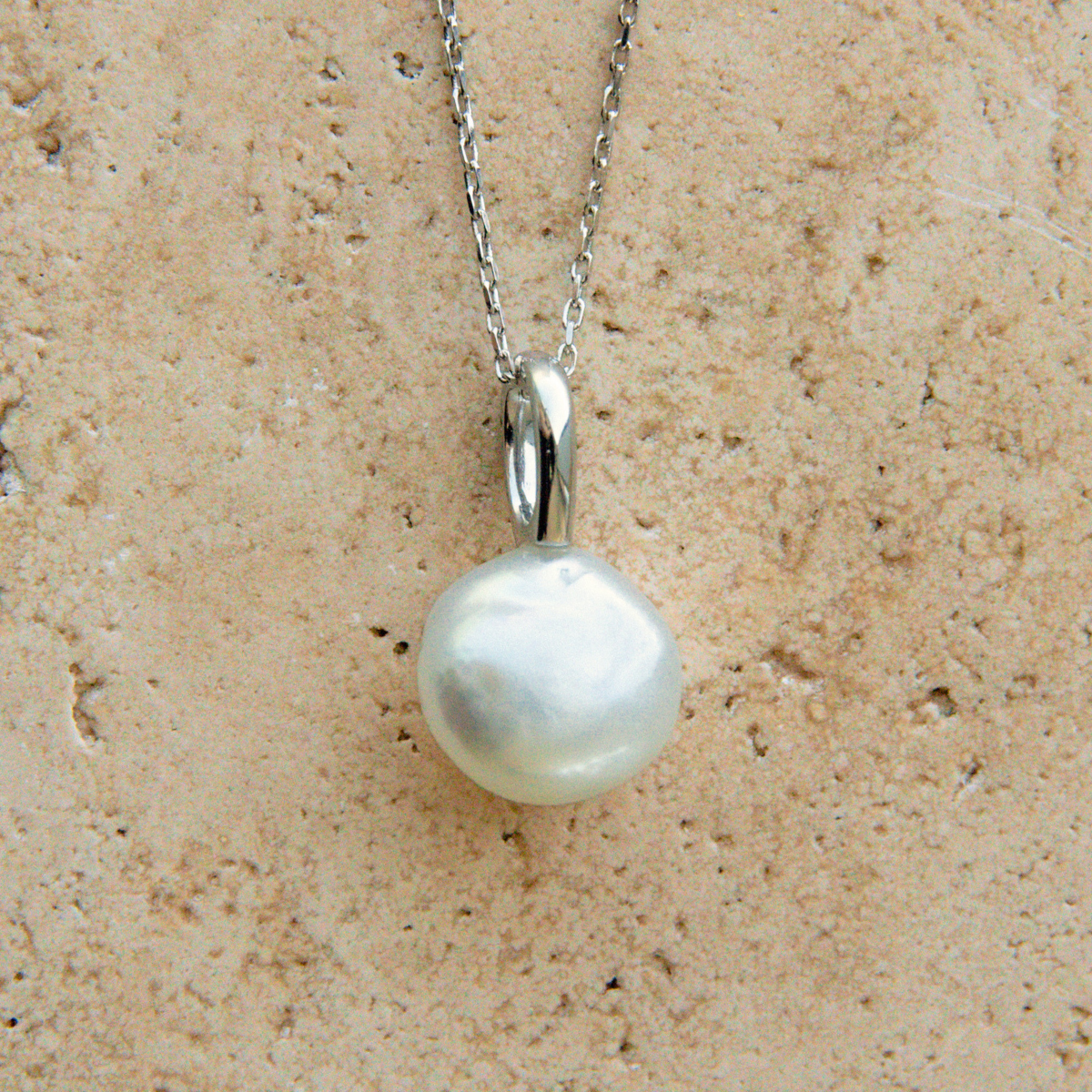 Pearl necklace on a beige stone background