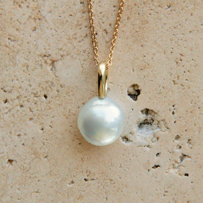 Pearl necklace with gold chain on a textured beige background