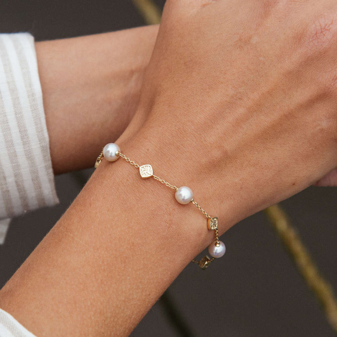 A woman wears her elegant Seagrass Pearl Bracelet featuring Broken Bay (NSW) grown Australian Akoya pearls, linked together on a gold chain