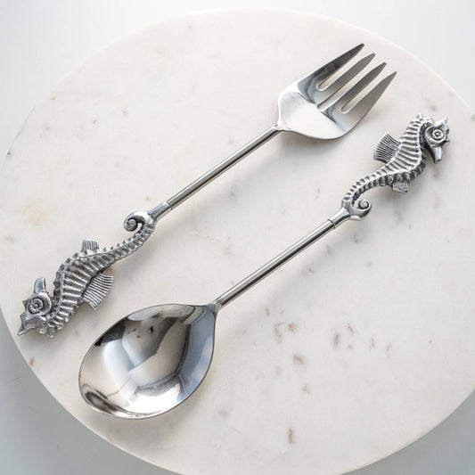 Serving spoon and fork with seahorse handles on a marble surface